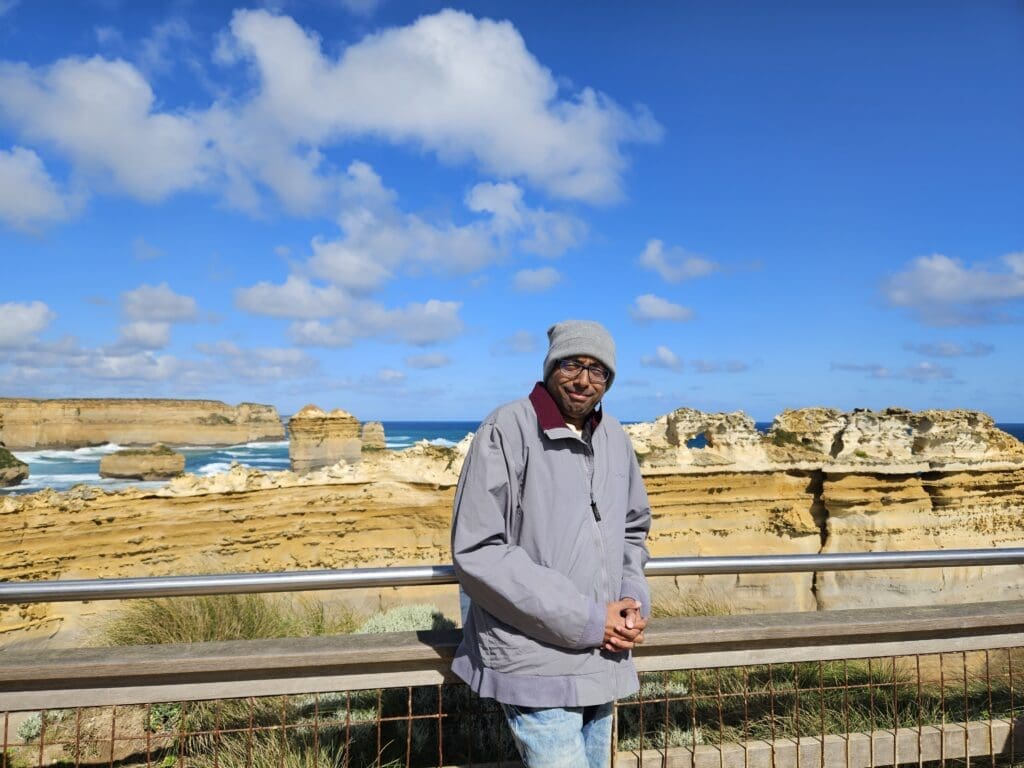 a man posing in front of a cliff facing coast